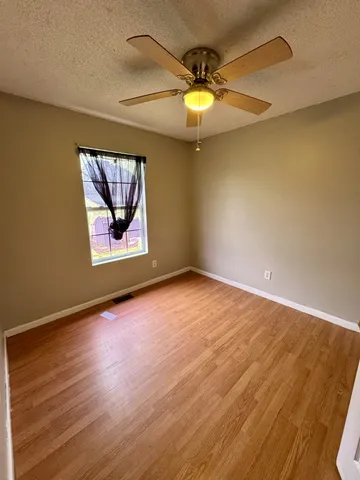 an empty room with wooden floor and fan
