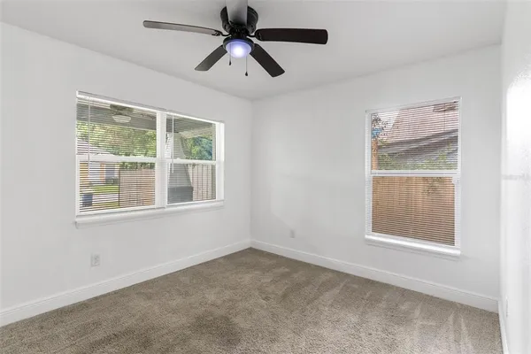 an empty room with a window and a fan