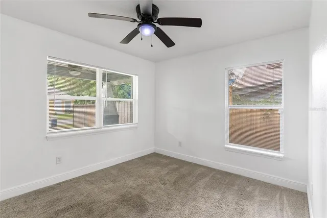 an empty room with a window and a fan