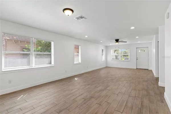 an empty room with wooden floor and windows