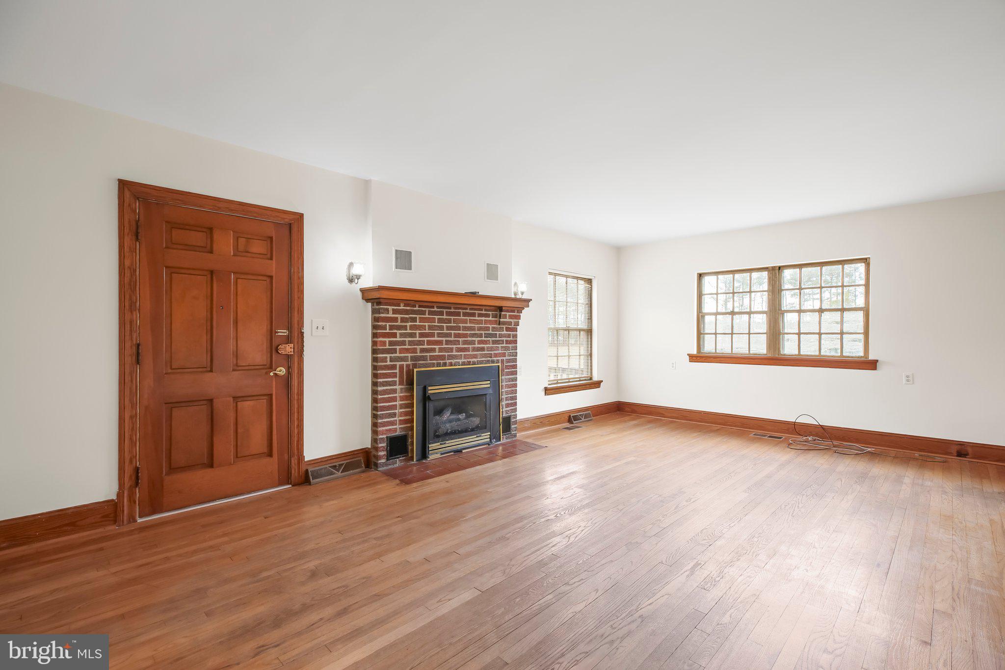 19192 Partlow Road Beaverdam, VA 23015 - Photo 4 of 26 an empty room with wooden floor fireplace and windows