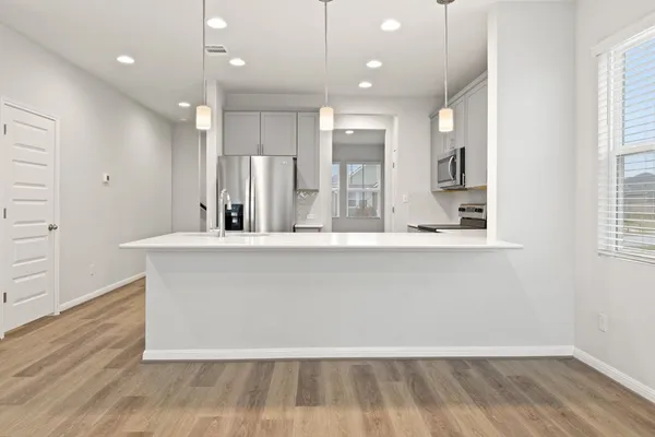 a large kitchen with kitchen island a large counter top and a wooden floor