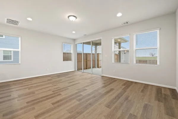 a view of empty room with wooden floor and window