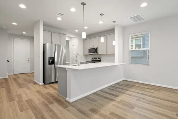 a kitchen with stainless steel appliances kitchen island granite countertop a refrigerator and a sink