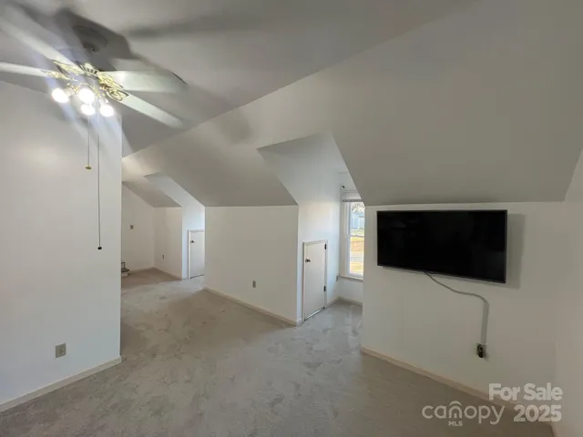 a view of an empty room with a flat screen tv and kitchen view
