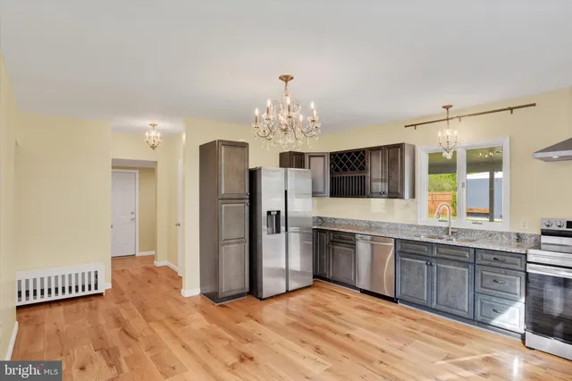 a large kitchen with stainless steel appliances a large kitchen island a sink dishwasher a refrigerator and a fireplace