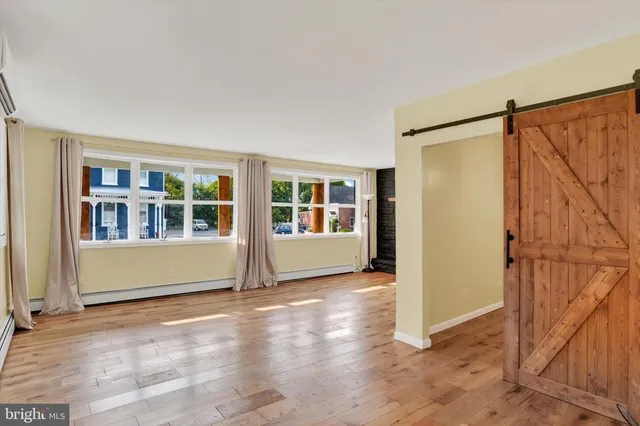 a view of an empty room with window and wooden floor