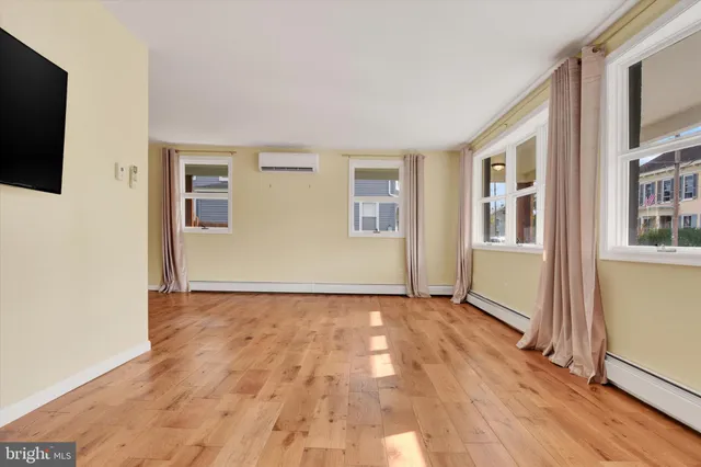 a view of an empty room with glass door and wooden floor