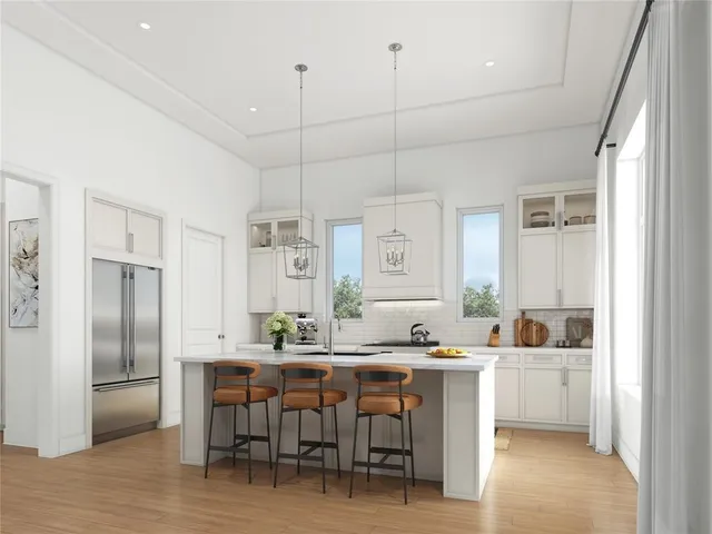 a kitchen with kitchen island a dining table chairs refrigerator and cabinets