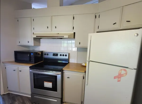 a white refrigerator freezer and a stove sitting inside of kitchen