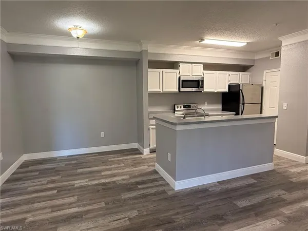 a room with kitchen island a sink appliances and cabinets