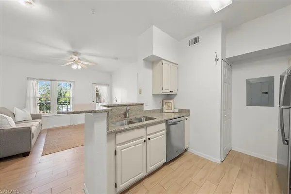 a kitchen with a sink dishwasher a stove and white cabinets with wooden floor