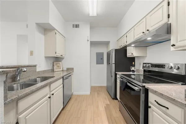 a kitchen with stainless steel appliances granite countertop a sink a stove and a refrigerator