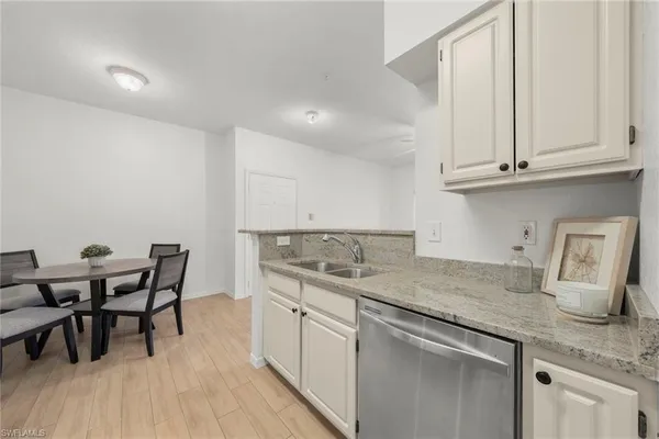 a kitchen with stainless steel appliances granite countertop a sink dishwasher and cabinets with wooden floor