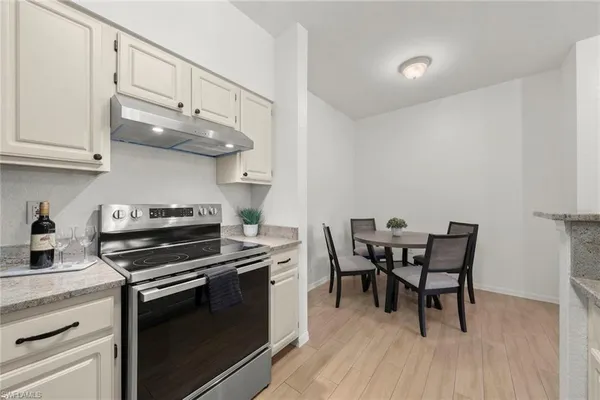 a kitchen with stainless steel appliances a white table chairs and a wooden floor