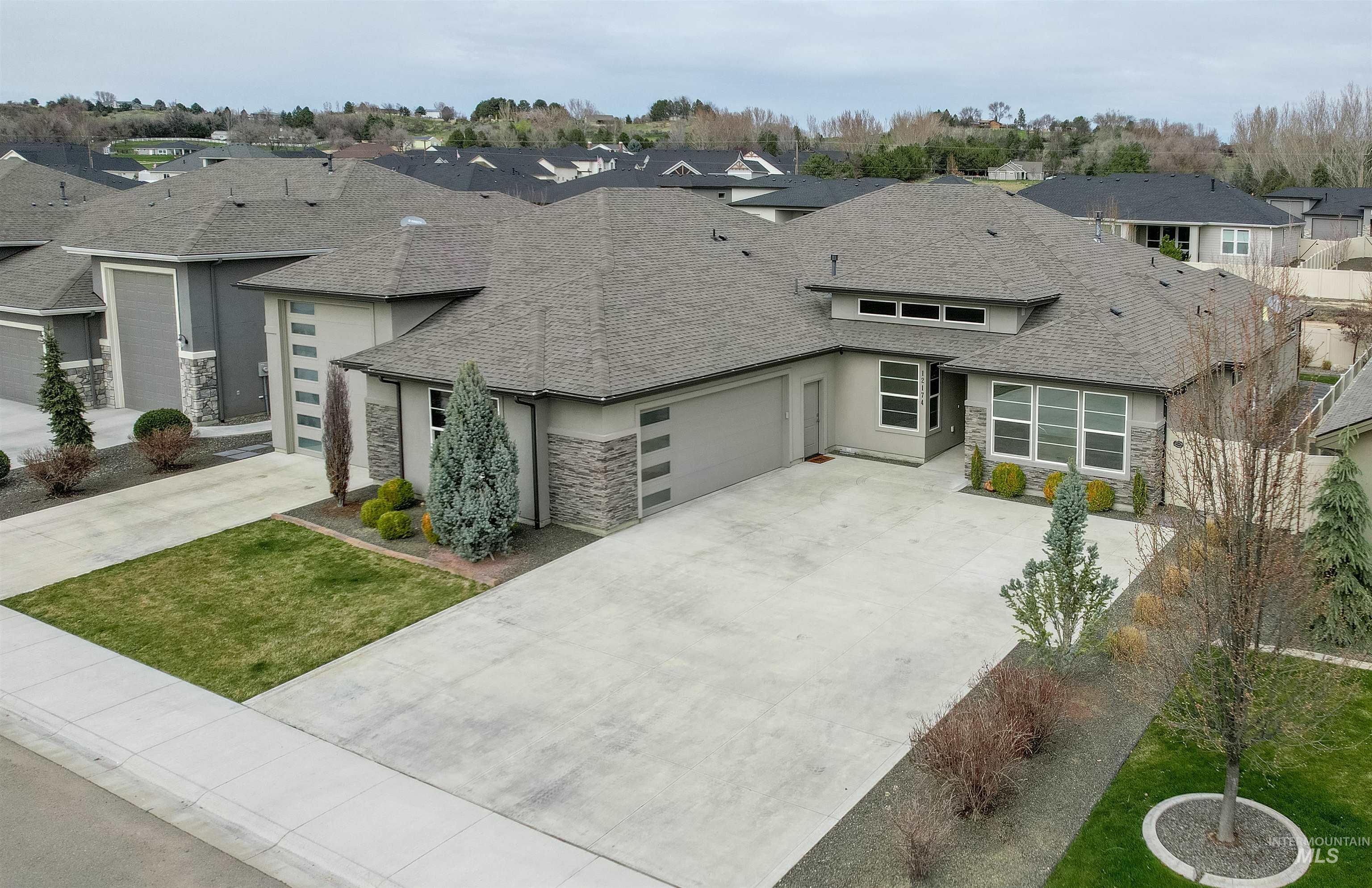 12174 West Lacerta Street Star, ID 83669 - Photo 1 of 49 View of front of house featuring stone siding, a residential view, a garage, concrete driveway, and roof with shingles