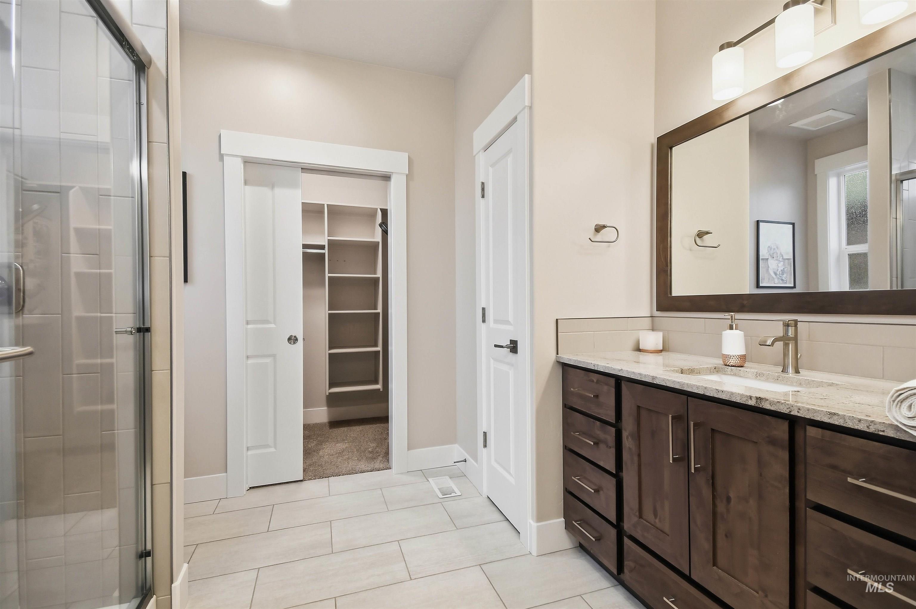 12174 West Lacerta Street Star, ID 83669 - Photo 32 of 49 Full bathroom featuring vanity, a stall shower, light tile patterned floors, and a spacious closet