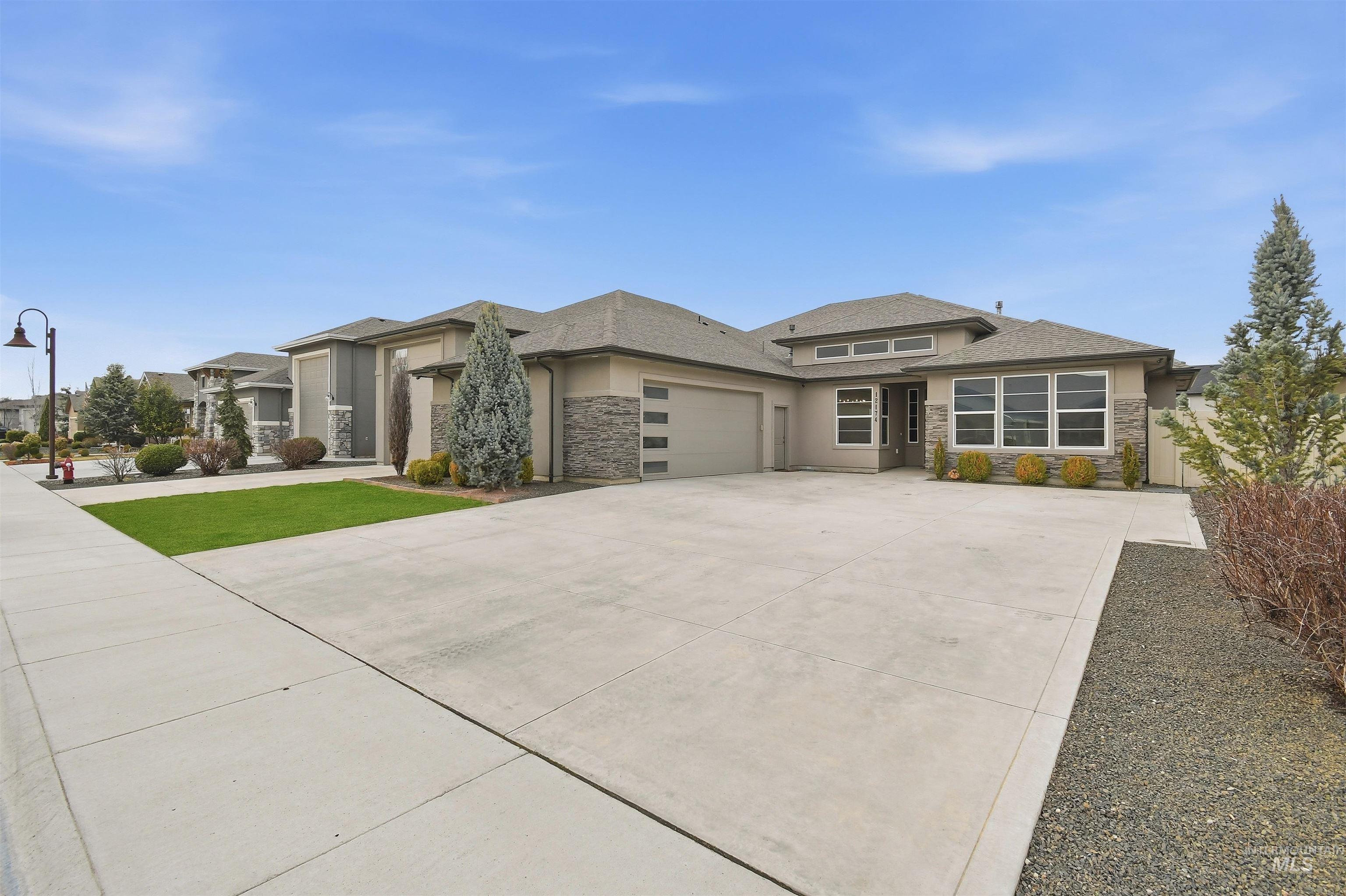 12174 West Lacerta Street Star, ID 83669 - Photo 4 of 49 Prairie-style home featuring stone siding, a garage, driveway, and stucco siding