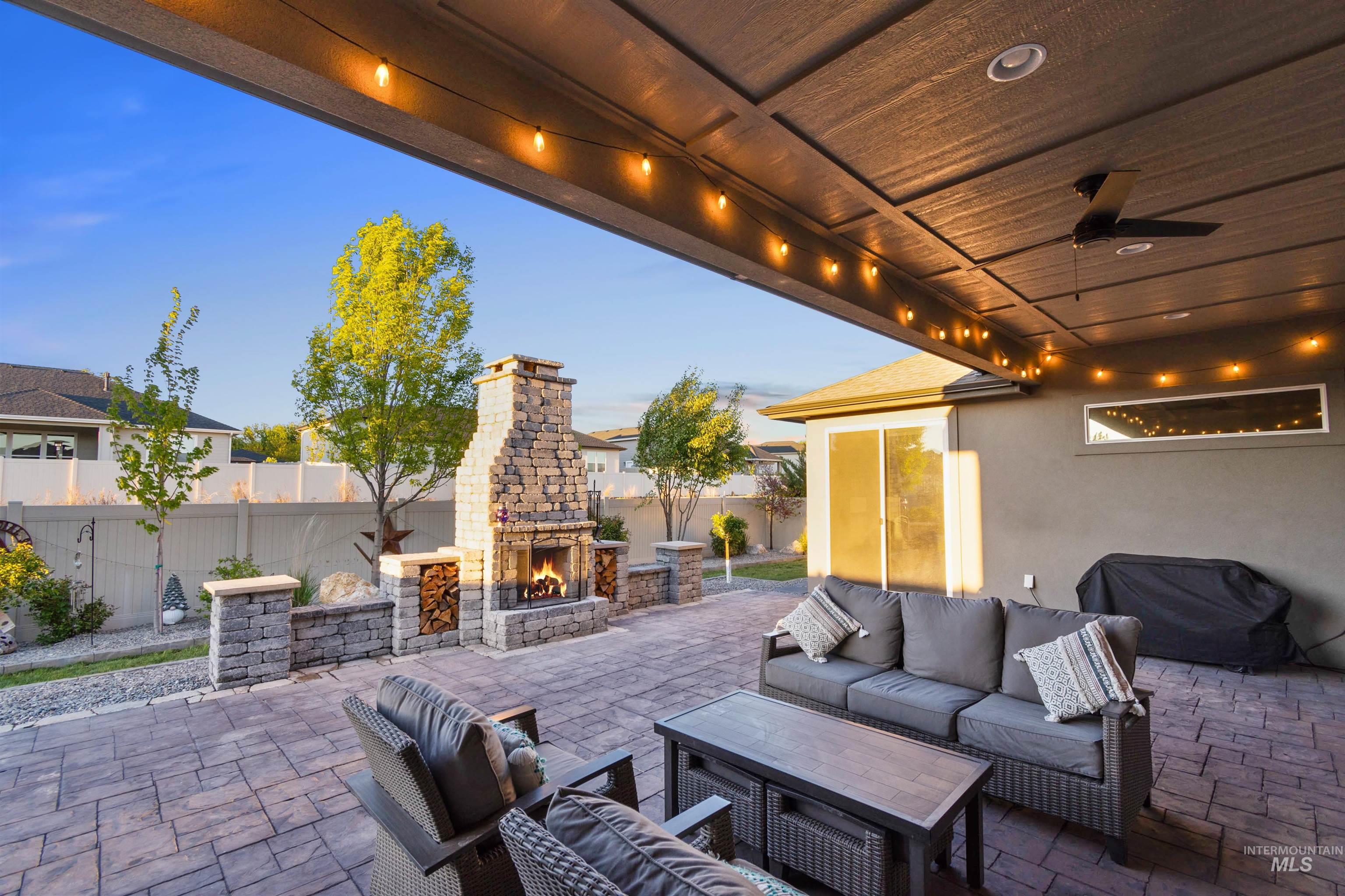 12174 West Lacerta Street Star, ID 83669 - Photo 39 of 49 Fenced backyard with a patio, an outdoor living space with a fireplace, and a ceiling fan