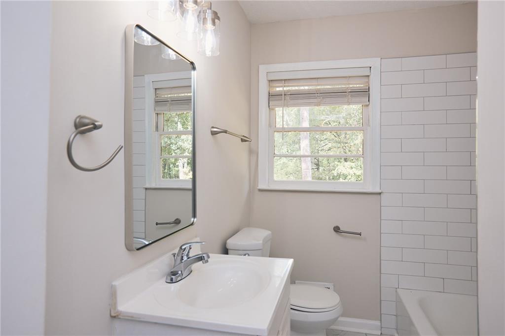 2058 River Road Ellenwood, GA 30294 - Photo 5 of 14 a bathroom with a toilet a sink a mirror and a window