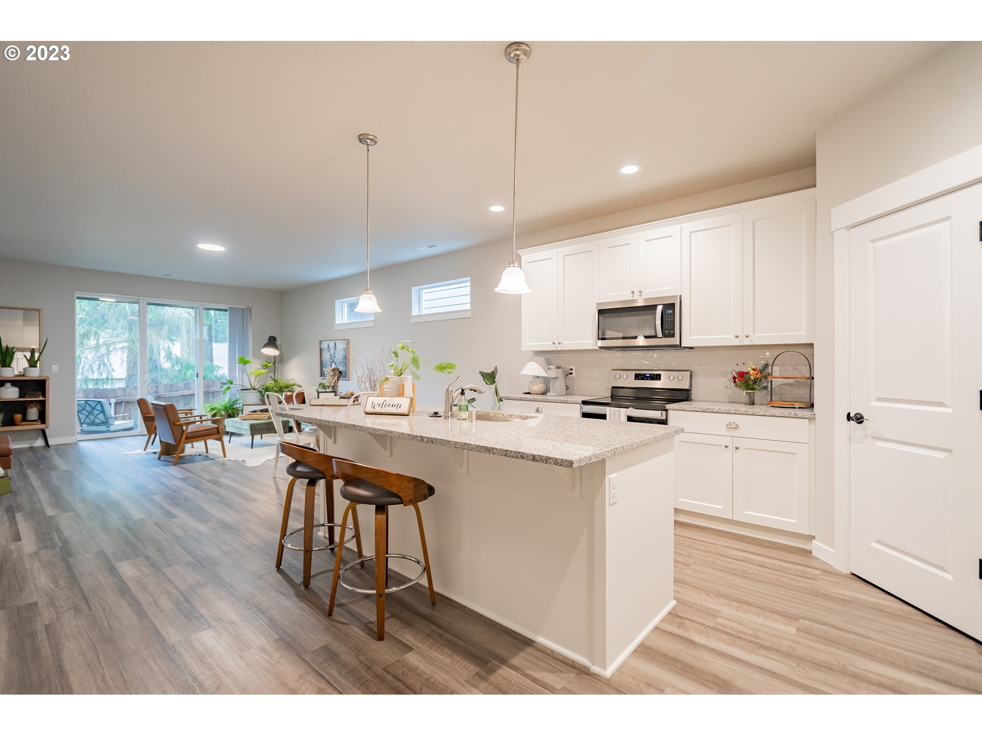 7111 South 13th Street Ridgefield, WA 98642 - Photo 8 of 33 a kitchen with stainless steel appliances granite countertop a refrigerator a stove top oven a sink dishwasher and white cabinets with wooden floor