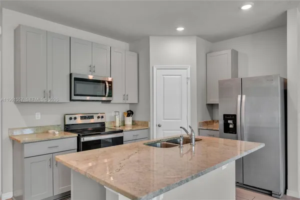 a kitchen with stainless steel appliances granite countertop a sink a stove and a refrigerator