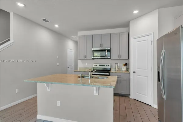 a kitchen with stainless steel appliances a refrigerator a stove a sink and white cabinets