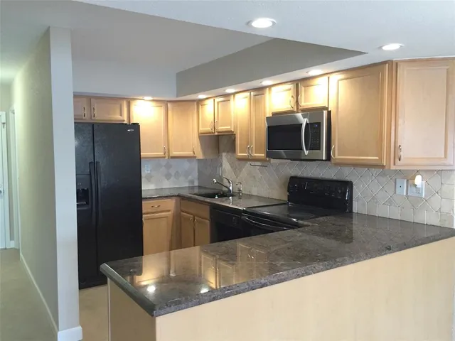 a kitchen with stainless steel appliances granite countertop a refrigerator a sink a stove a microwave a counter space and cabinets