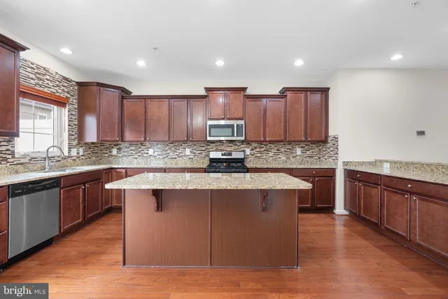 a large kitchen with stainless steel appliances granite countertop a stove sink and cabinets