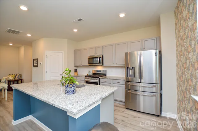 a kitchen with stainless steel appliances granite countertop a sink a refrigerator and a granite counter tops