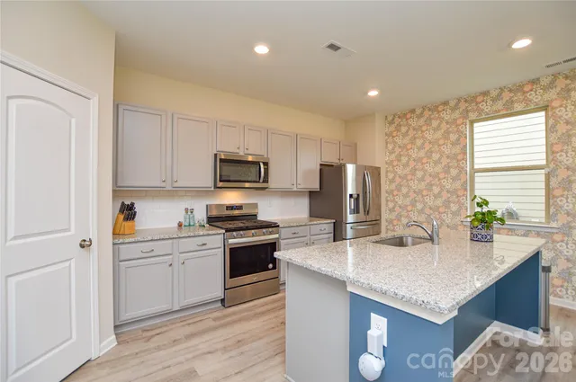 a kitchen with stainless steel appliances granite countertop a sink dishwasher stove and refrigerator with wooden floor