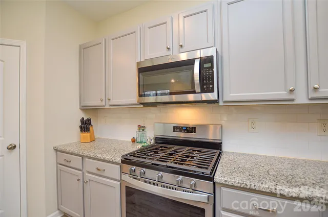 a kitchen with granite countertop white cabinets and stainless steel appliances