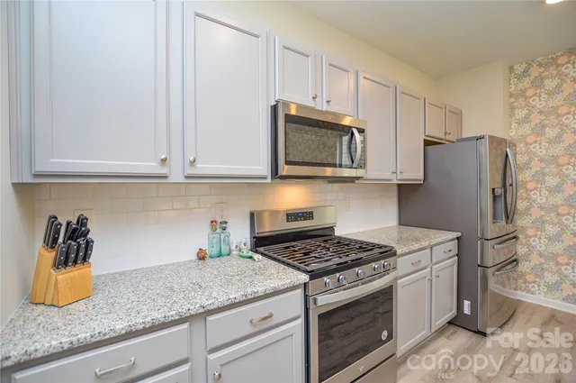 a kitchen with granite countertop cabinets stainless steel appliances and a counter space
