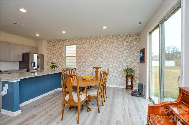a dining room with stainless steel appliances granite countertop furniture wooden floor and a rug