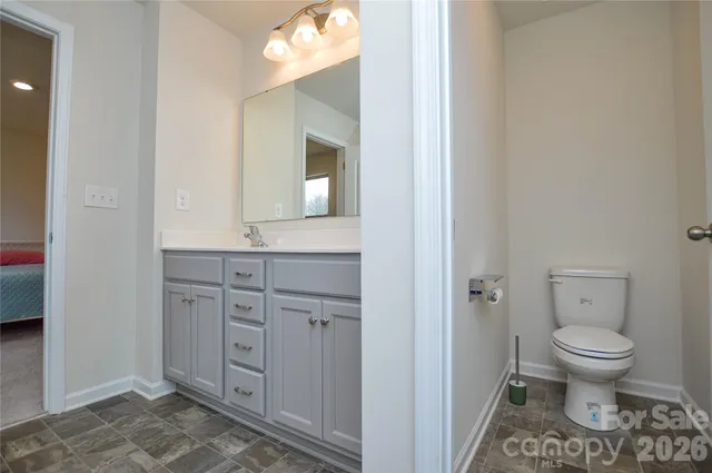 a bathroom with a granite countertop toilet sink and mirror