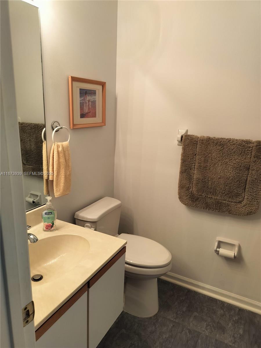 1002 Keystone Drive, Unit F Jupiter, FL 33458 - Photo 8 of 10 a bathroom with a toilet sink and mirror