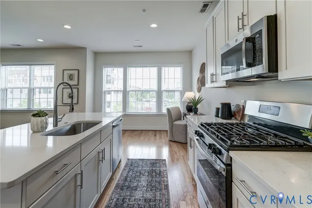 a kitchen with stainless steel appliances a sink a stove cabinets and a counter top space