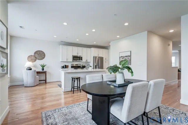 a kitchen with stainless steel appliances granite countertop a table chairs and a refrigerator