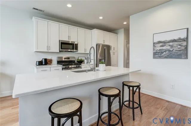 a kitchen with stainless steel appliances a sink a stove a refrigerator cabinets and dining table