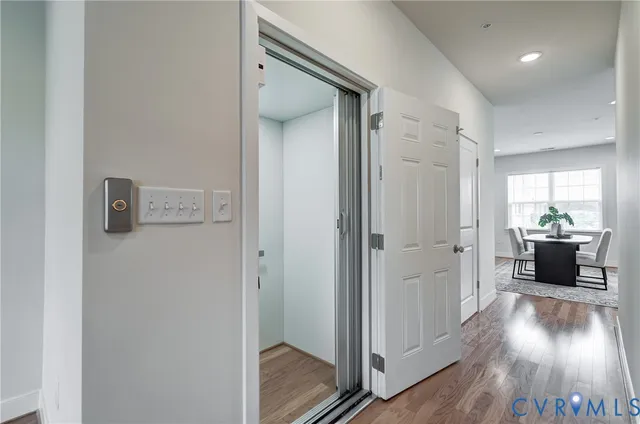 a view of a hallway view with wooden floor and a bathroom