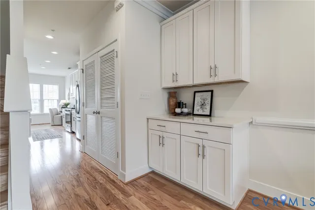 a hallway with white cabinets and wooden floor