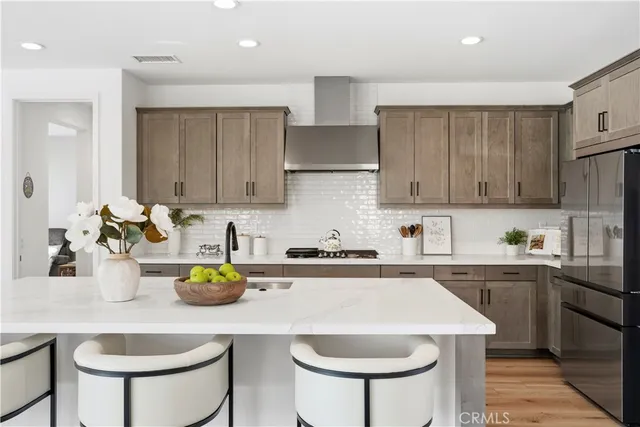 a kitchen with stainless steel appliances a refrigerator a stove a sink dishwasher a dining table and chairs with wooden floor