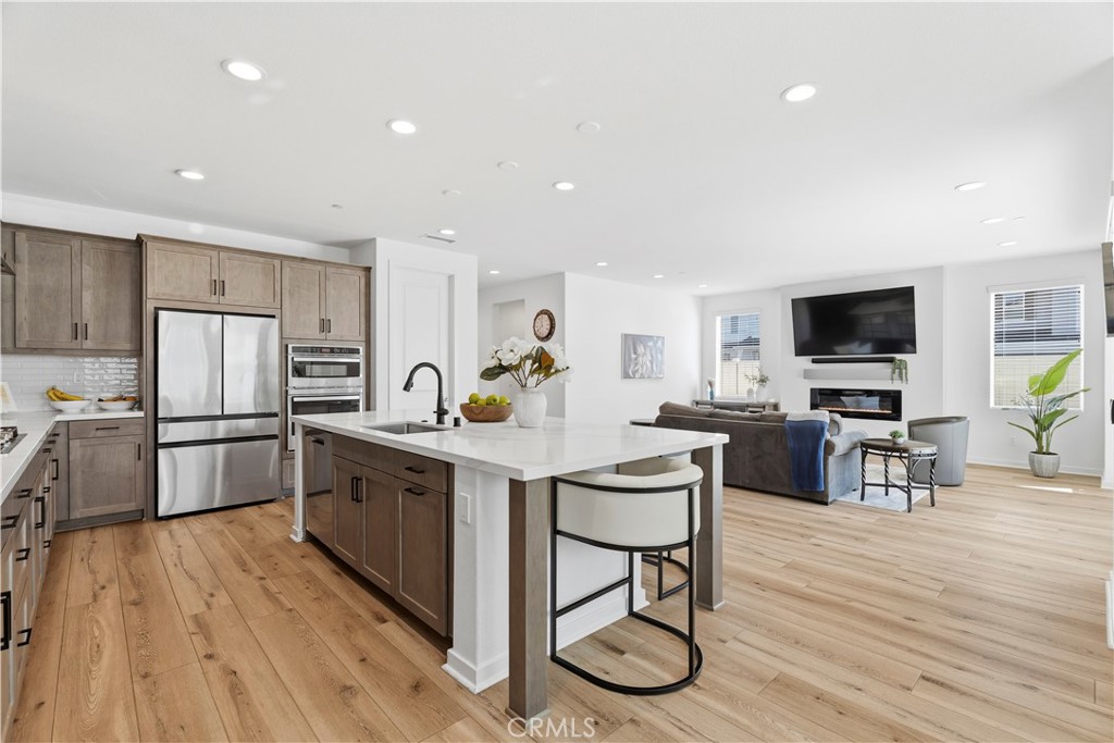 18100 Tableau Way Saugus, CA 91350 - Photo 16 of 63 a kitchen with stainless steel appliances a refrigerator a stove a sink dishwasher a dining table and chairs with wooden floor
