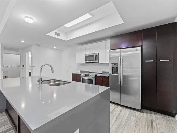 a kitchen with stainless steel appliances granite countertop a refrigerator a stove and a sink with wooden floor
