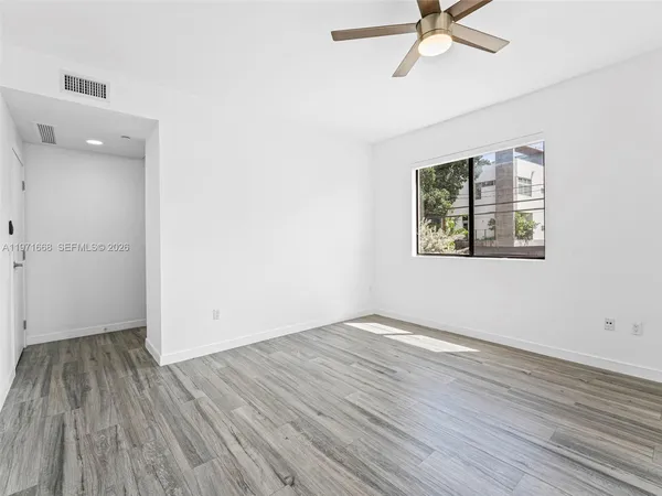 an empty room with a hardwood and ceiling fan