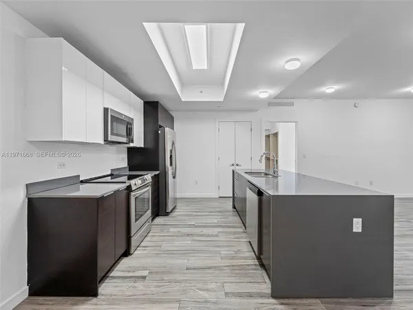 a large kitchen with stainless steel appliances a large counter top a stove a chimney a sink and a refrigerator