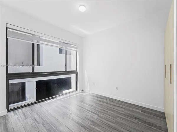 a view of an empty room with wooden floor and a window