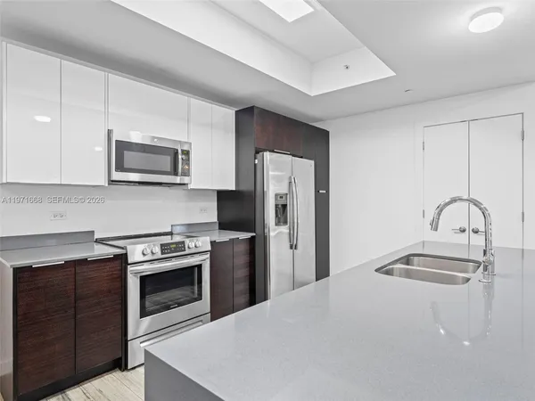 a kitchen with granite countertop a refrigerator stove and sink