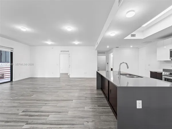 a large kitchen with stainless steel appliances a large counter top a stove and a refrigerator