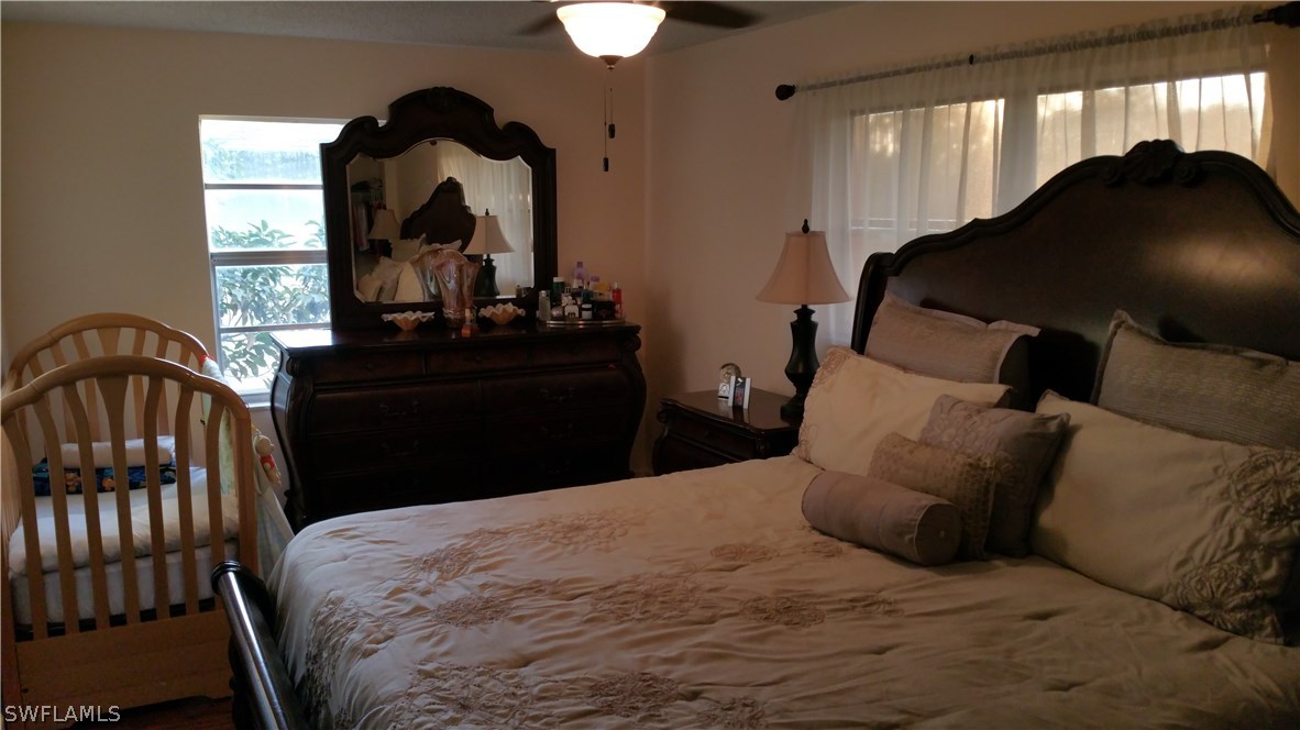 24 Colorado Road Lehigh Acres, FL 33936 - Photo 5 of 12 a bedroom with a bed and a chandelier
